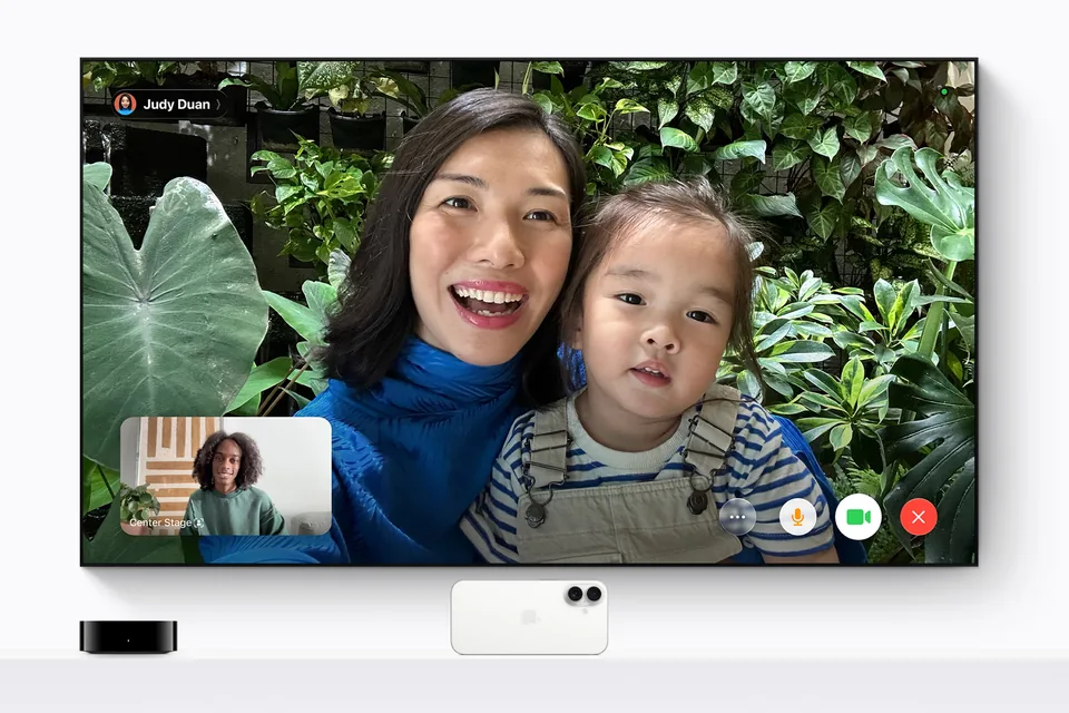 FaceTime-Anruf auf einem Wandfernseher, darunter Streaming-Box und ein iPhone als Kamera