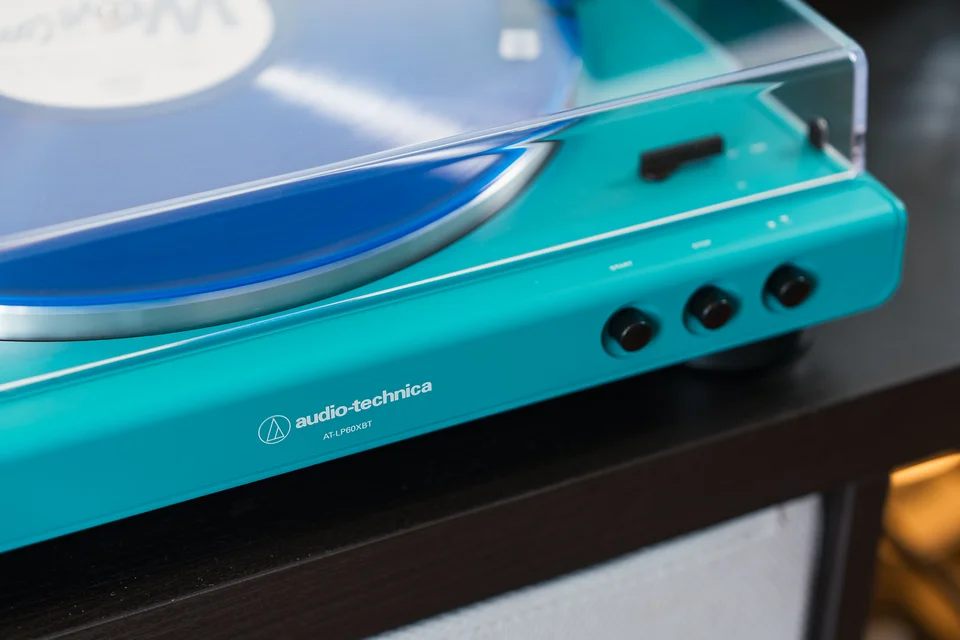 Front des Audio-Technica AT-LP60XBT in Teal mit Logo und drei Bedientasten