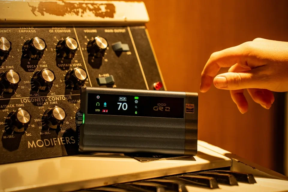 Mobiler DAC-Kopfhörerverstärker auf einem analogen Synthesizer, eine Hand greift zum Display