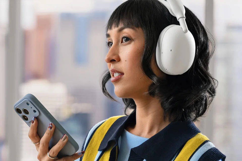 Frau mit Logitech Zone Vibe Pro in Off-White telefoniert mit dem Smartphone in der Hand