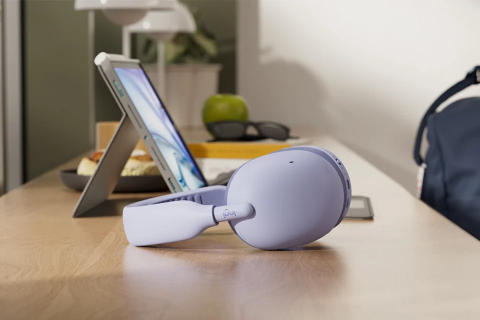 Logitech Zone Vibe Pro in Lilac liegt auf einem Holztisch neben einem Tablet
