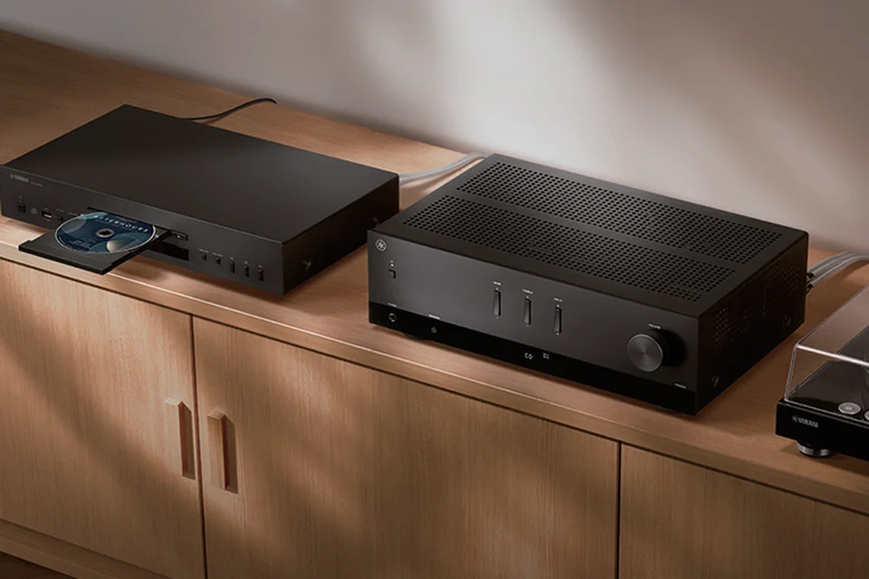 Yamaha R200A neben einem CD-Player mit geöffneter Schublade auf einem Holzsideboard